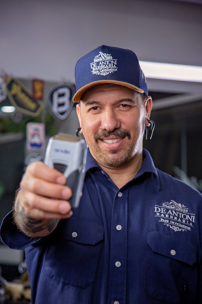 The Art of Drawing Readers In: Your attractive post title goes here Smiling barber with mustache holds clippers in a modern barbershop.