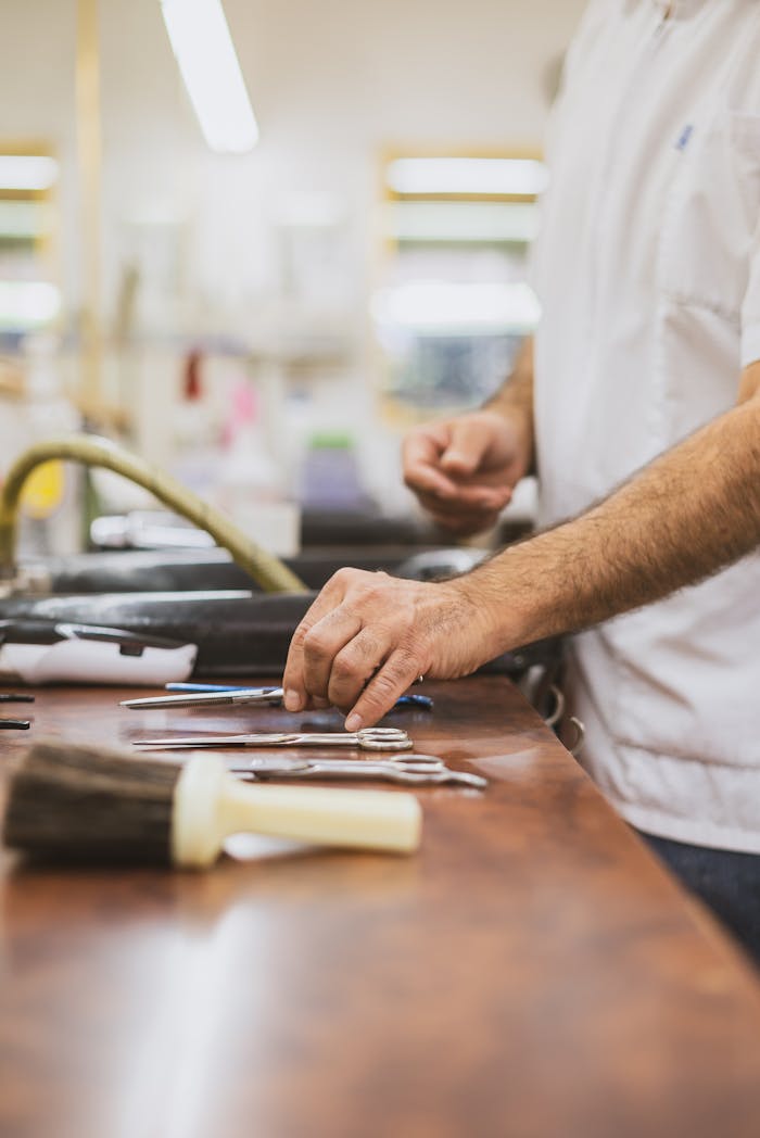 Mastering the First Impression: Your intriguing post title goes here Close-up of a barber arranging scissors and combs on a wooden counter.